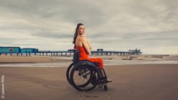 Photo: Samanta Bullock in her wheelchair at the beach. She is wearing a chic red dress; Copyright: Lawson Filho