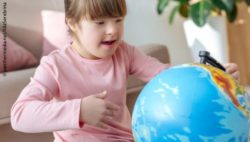 Photo: Girl with trisomy 21 looking at a globe; Copyright: panthermedia.net/AllaSerebrina