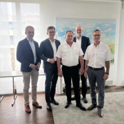 Five men stand side by side in a conference room