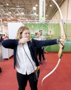 Photo: Woman shooting an arrow in the Sports Center at REHACARE; Copyright: Messe Düsseldorf/Andreas Wiese