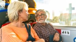 Two elderly people talking to each other in a bus