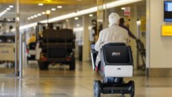 Person using a WHILL autonomous mobility device in Heathrow Airport Terminal 3