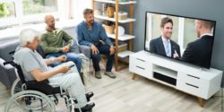 Photo: Three men, three generations. The oldest man sits in a wheelchair, the younger men sit on the couch in front of a TV; Copyright: PantherMedia / Andriy Popov